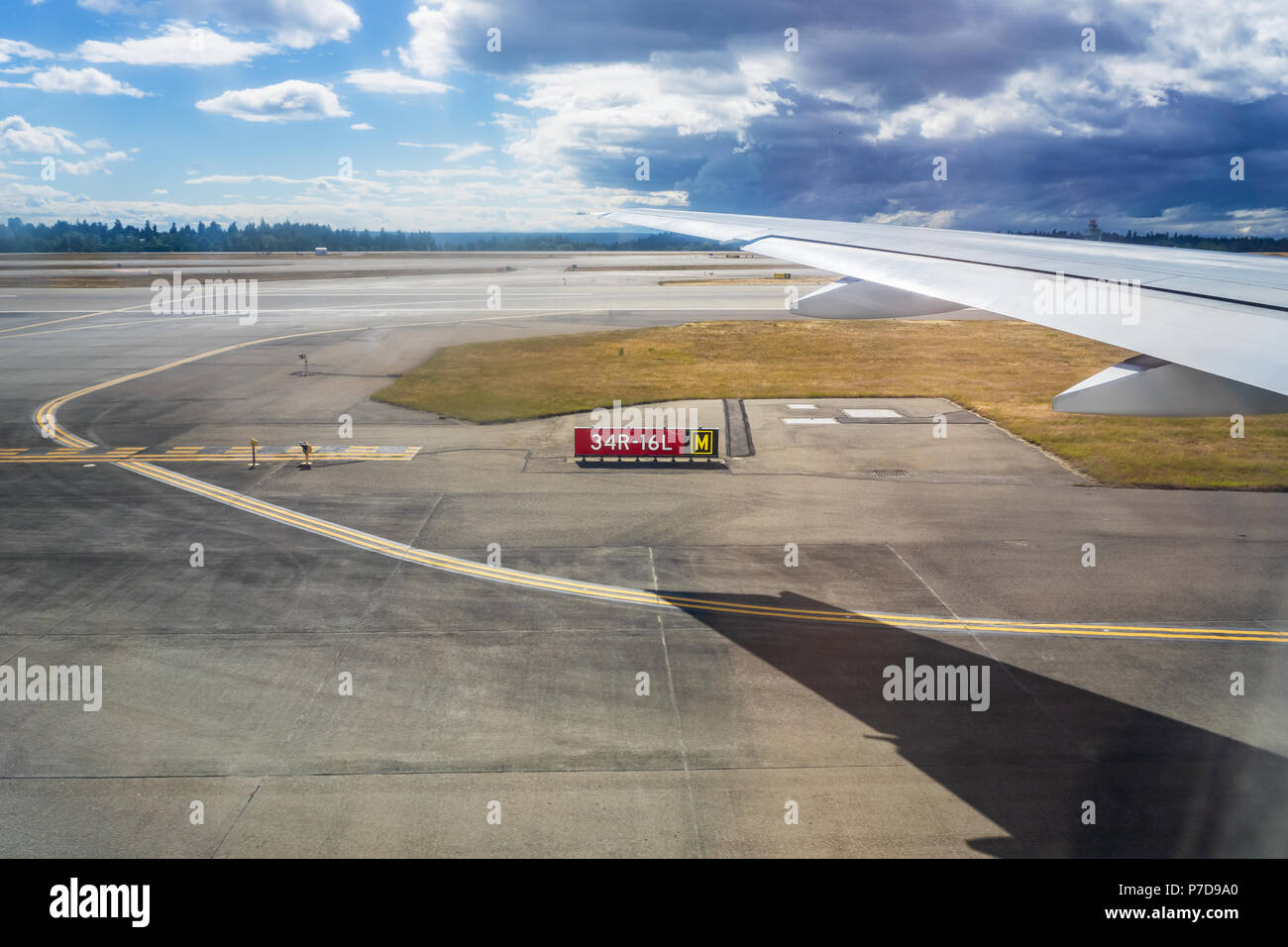 Ala di aeroplano con la sua ombra proiettata sulla pista durante il decollo. Concetto di viaggio. Foto Stock