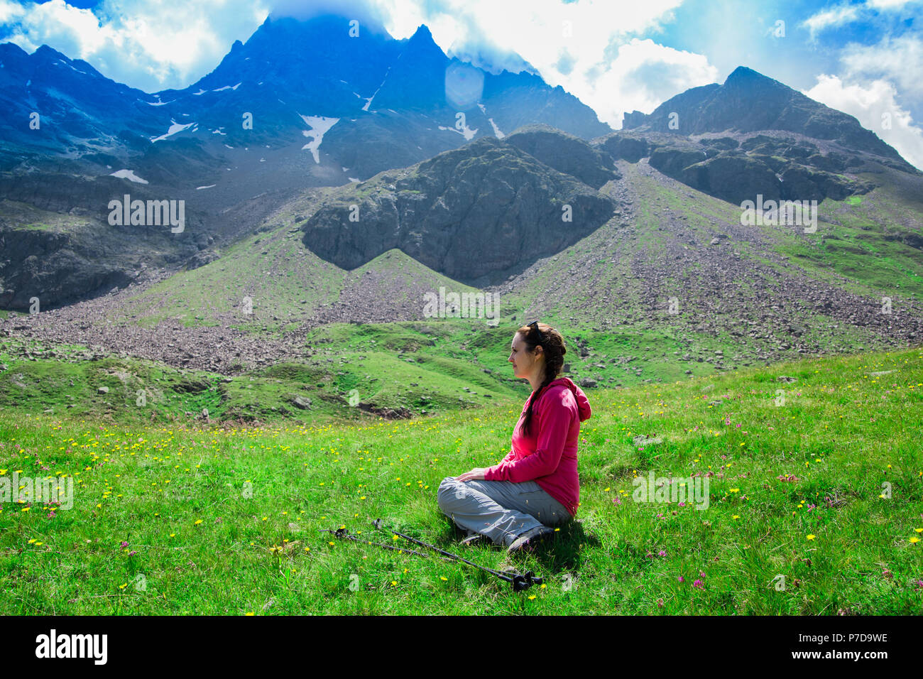 Donna seduta sul prato dopo una lunga camminata in montagna Foto Stock