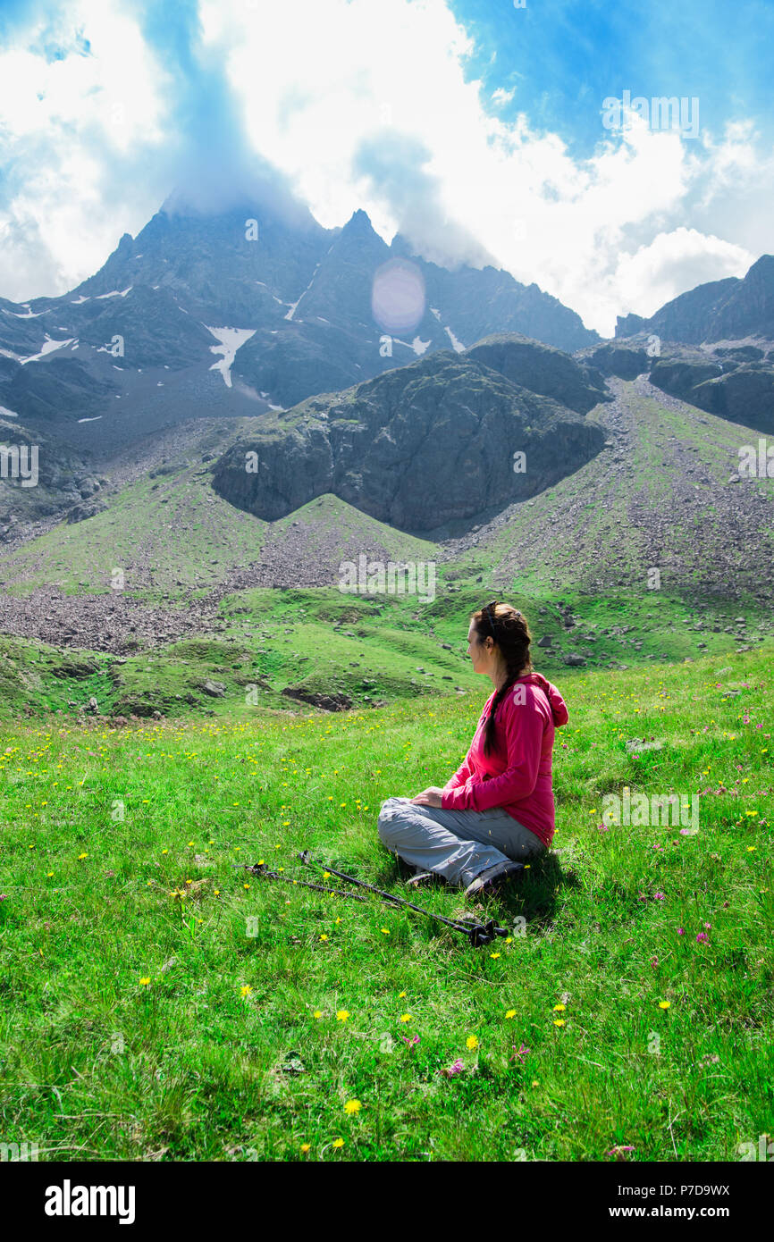 Donna seduta sul prato dopo una lunga camminata in montagna Foto Stock