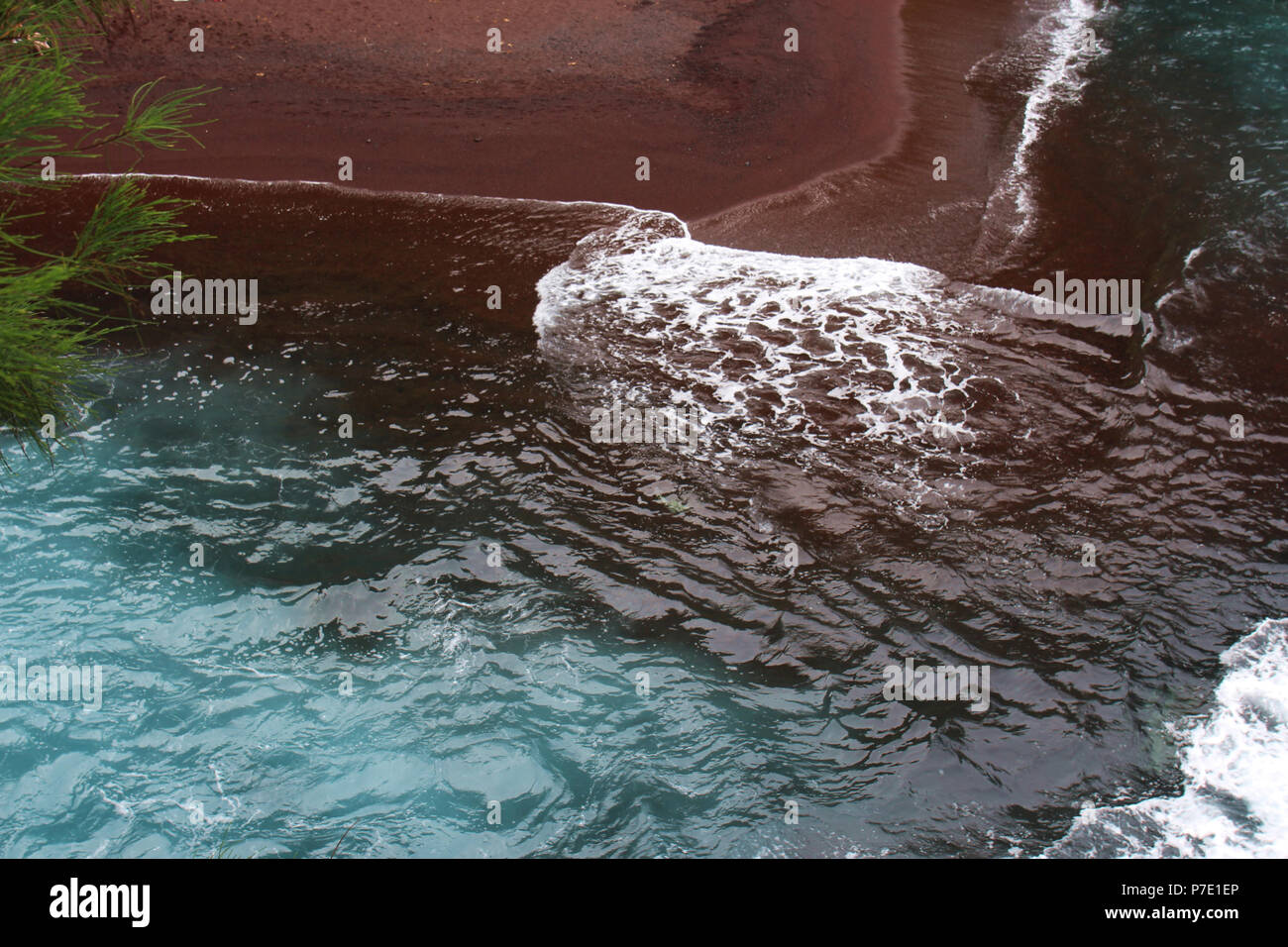 In prossimità delle acque turchesi dell'Oceano Pacifico rotoli sulla sabbia rossa della sabbia rossa sulla spiaggia Kaihalulu Bay, in Maui, Hawaii, STATI UNITI D'AMERICA Foto Stock