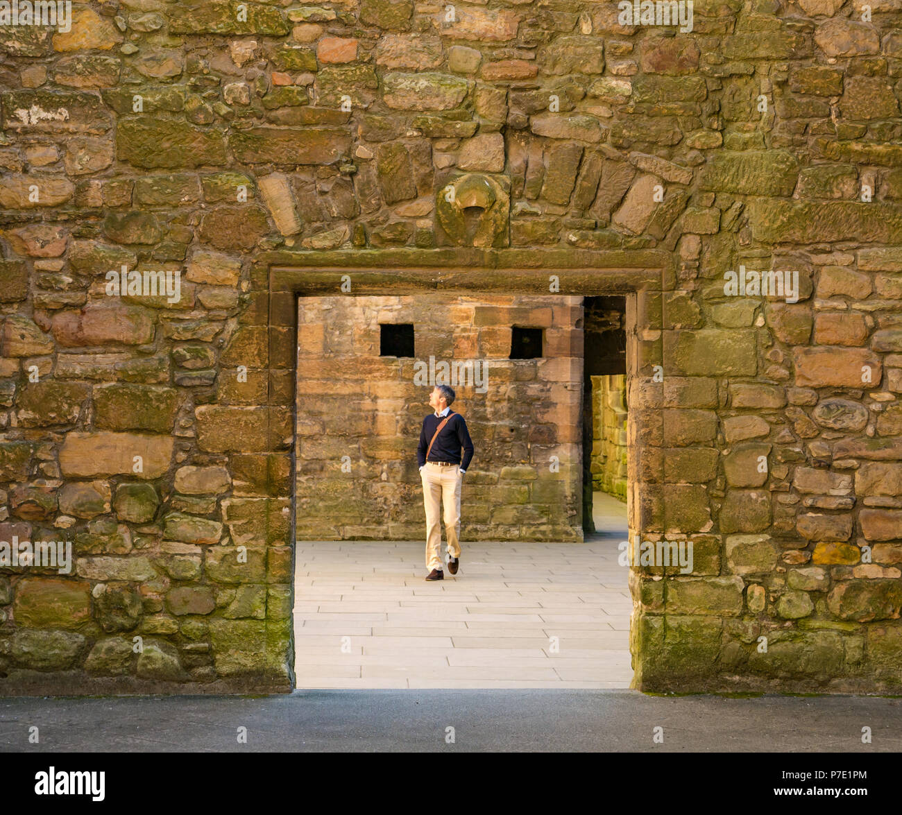 Turismo maschio incorniciato da porta a piedi attraverso rovinato palace, Linlithgow Palace, West Lothian, Scozia, Regno Unito Foto Stock