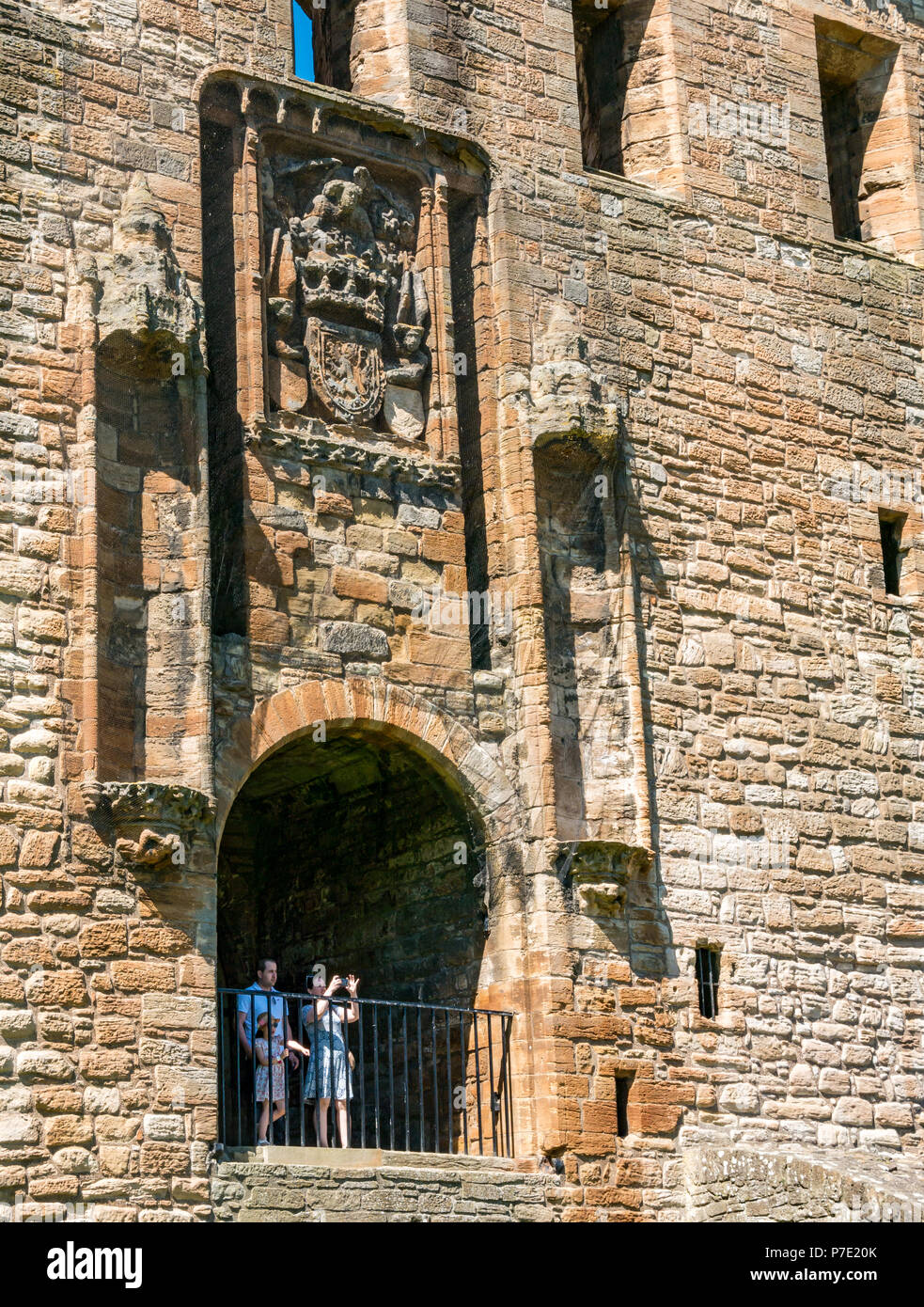 Visitatori incorniciato in ingresso in rovina che si affaccia su terreni con donna di scattare una foto, Linlithgow Palace, West Lothian, Scozia, Regno Unito Foto Stock