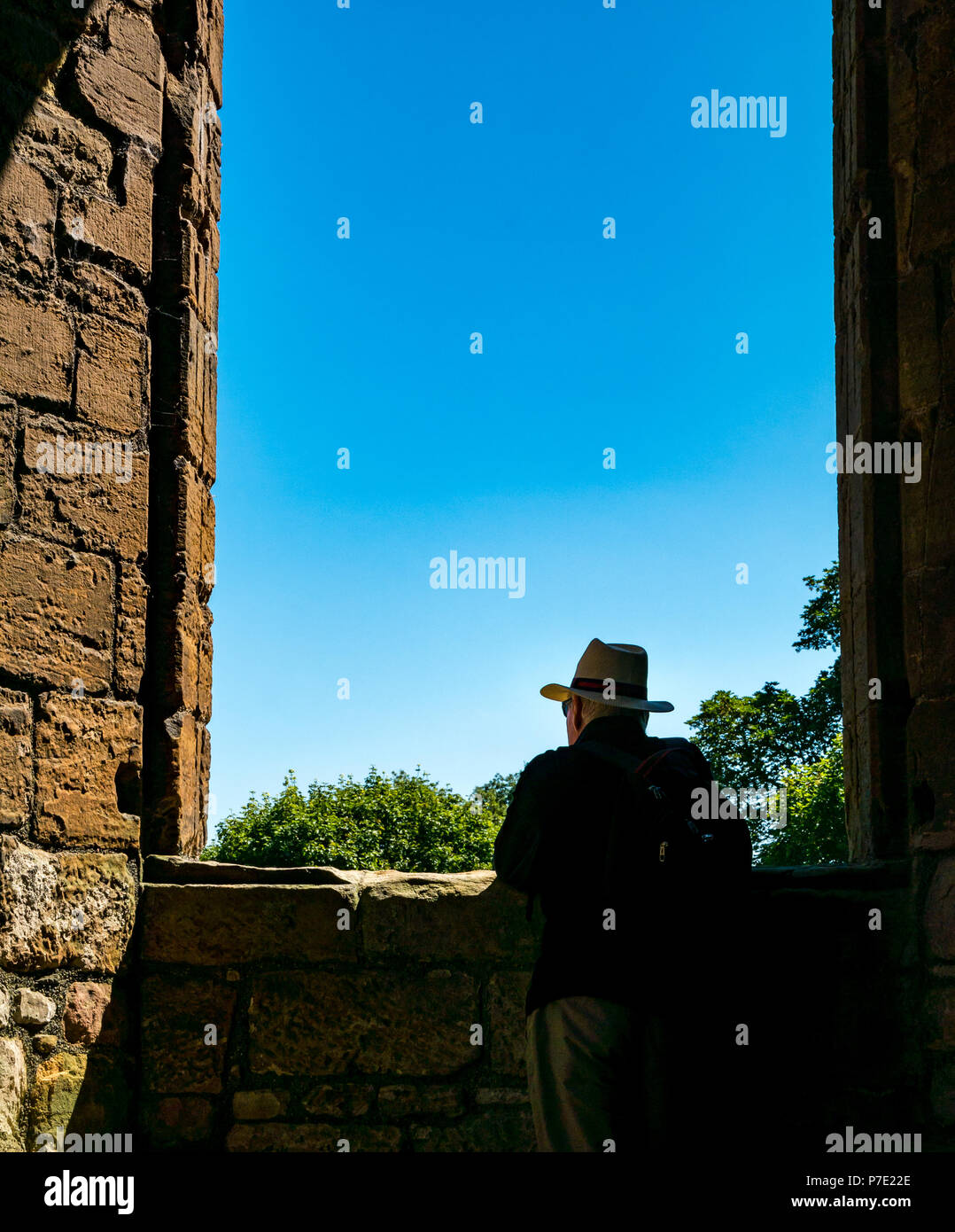 Incorniciato silhouette di un uomo che indossa cappello di Panama in rovina il telaio del finestrino con cielo blu, Linlithgow Palace, West Lothian, Scozia, Regno Unito Foto Stock