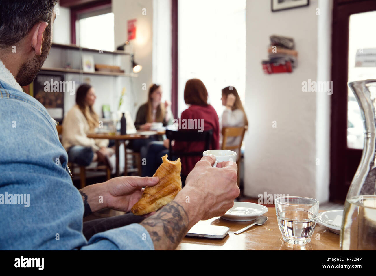 L'uomo avente la colazione, distratti dalle donne sul tavolo successivo Foto Stock