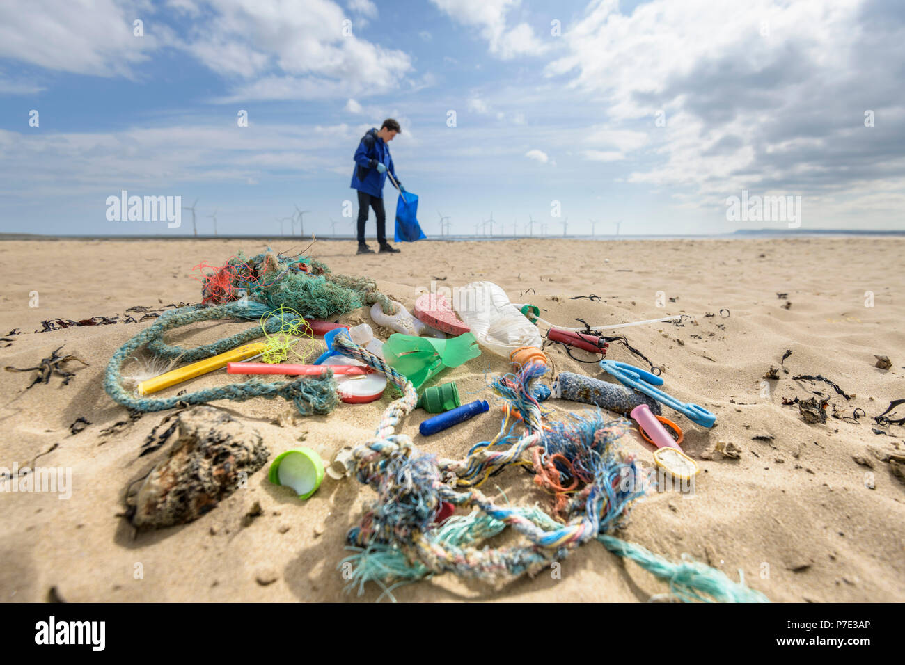 Man picking up inquinamento di plastica raccolte sulla spiaggia, North East England, Regno Unito Foto Stock