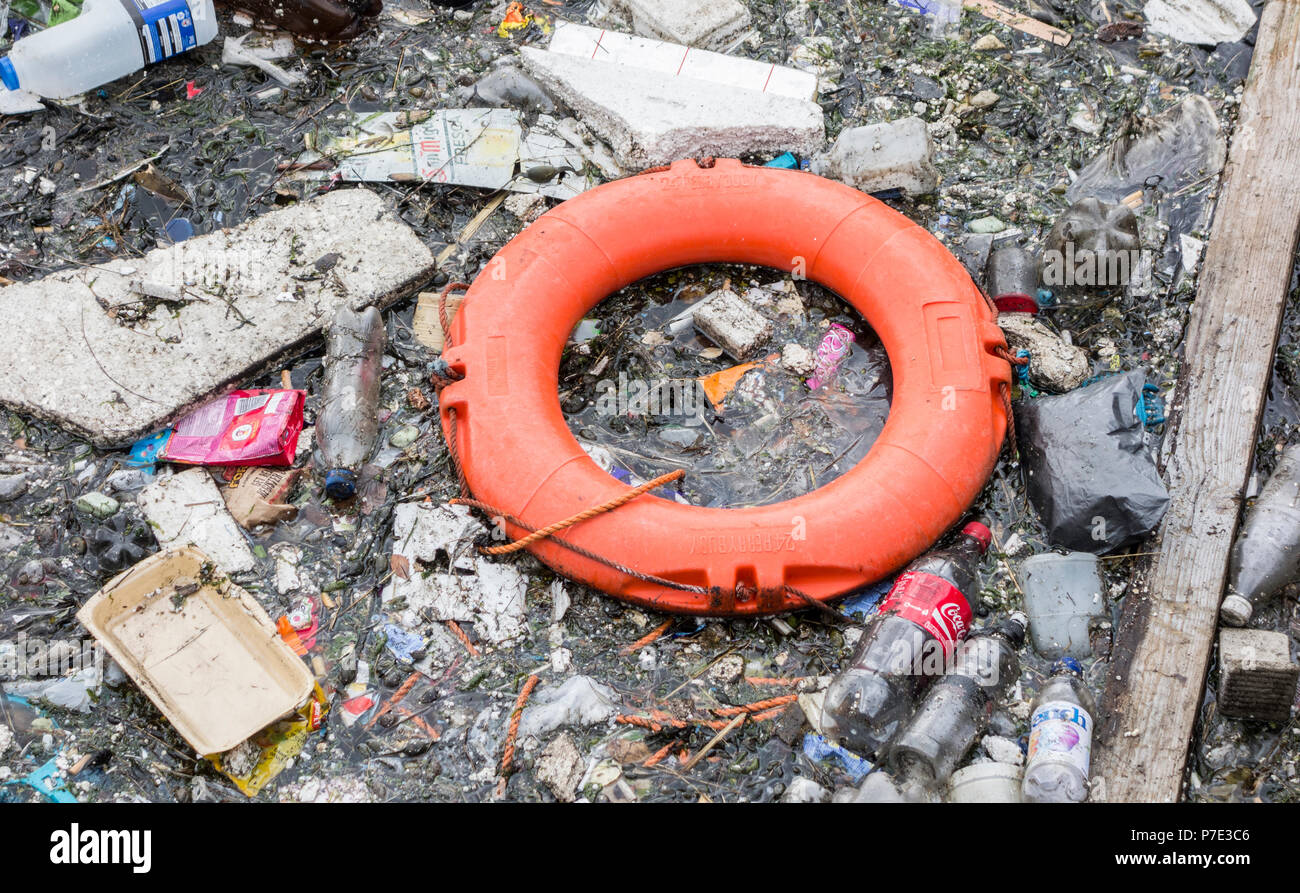 Bottiglie di plastica e spazzatura e lifebelt galleggiante nel fiume del Regno Unito. Foto Stock