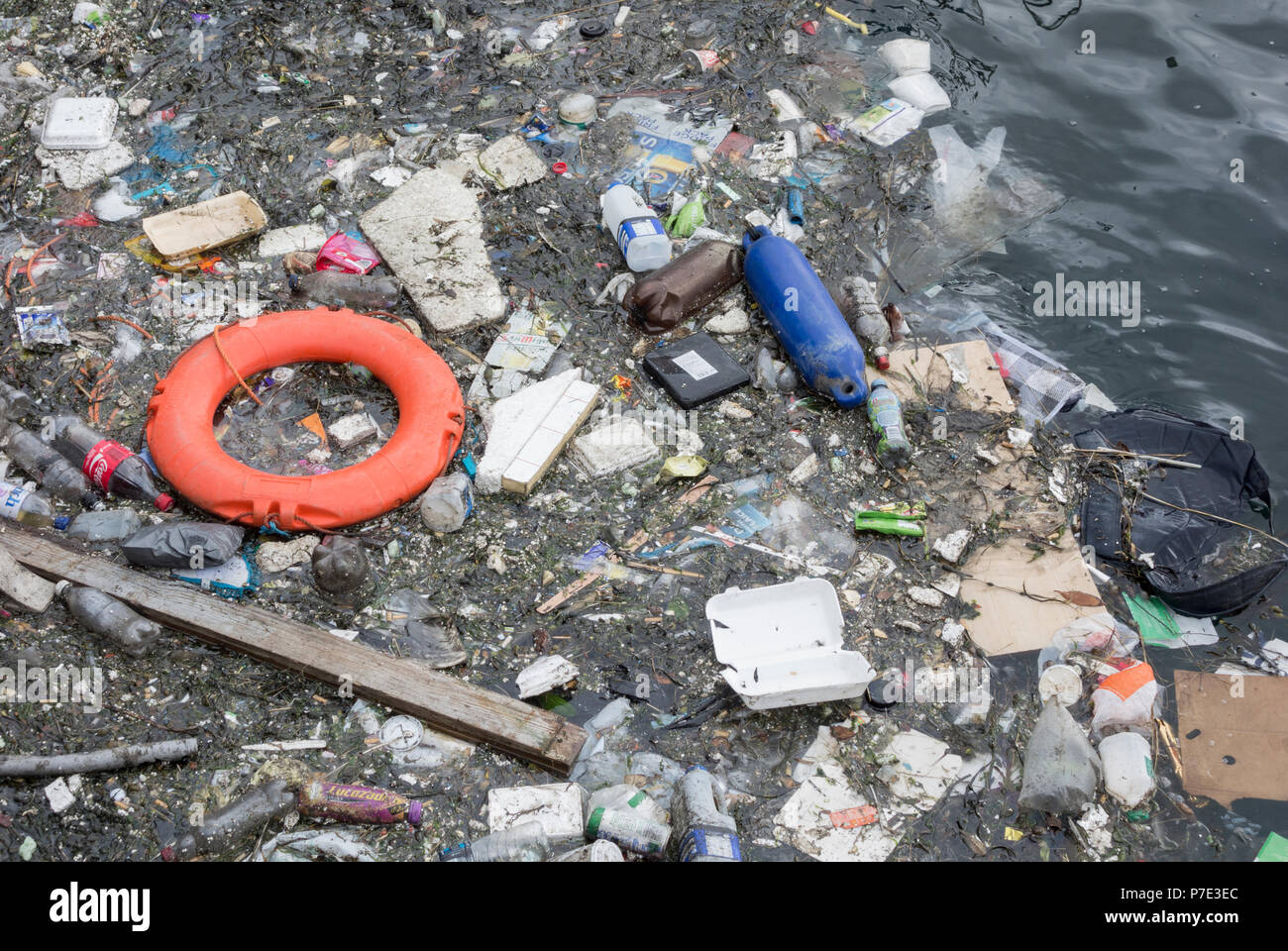 Bottiglie di plastica e spazzatura e lifebelt galleggiante nel fiume del Regno Unito. Foto Stock