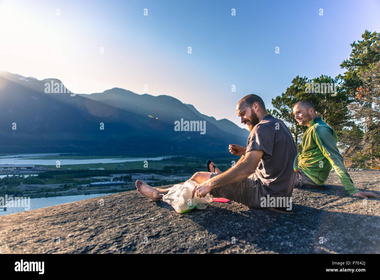 Amici rilassante sulla battuta di montagna che si affaccia sul lago, Squamish, Canada Foto Stock