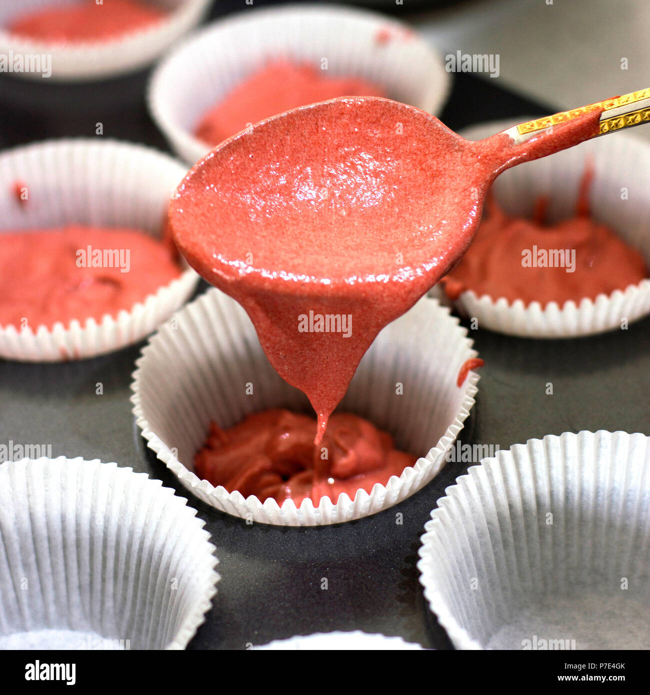 Rendendo i tortini. Riempimento dal cucchiaio con rosa forme di impasto per muffin Foto Stock