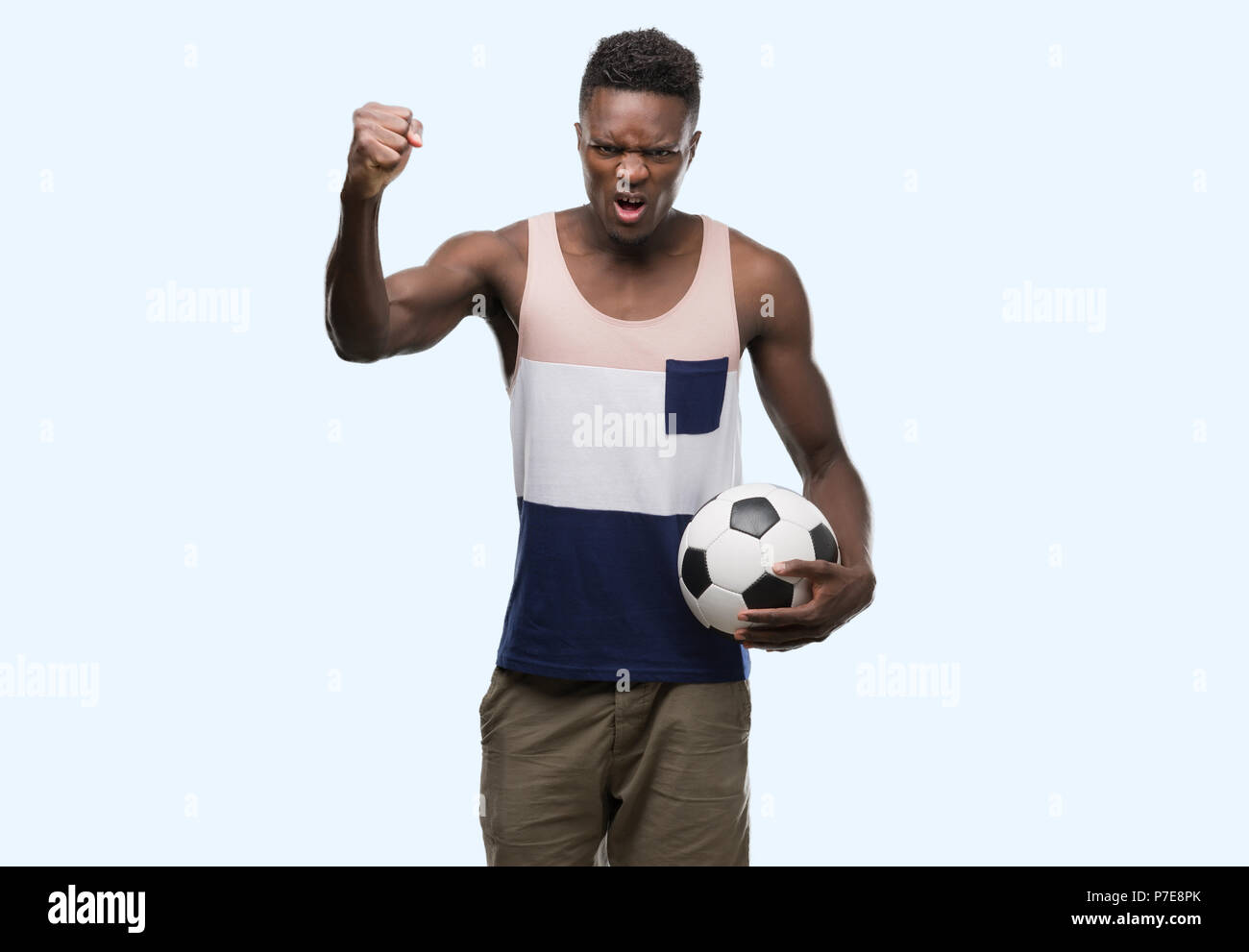 Giovane americano africano uomo azienda soccer football ball infastiditi e frustrato grida con rabbia, crazy e urla con la mano alzata, concetto di rabbia Foto Stock
