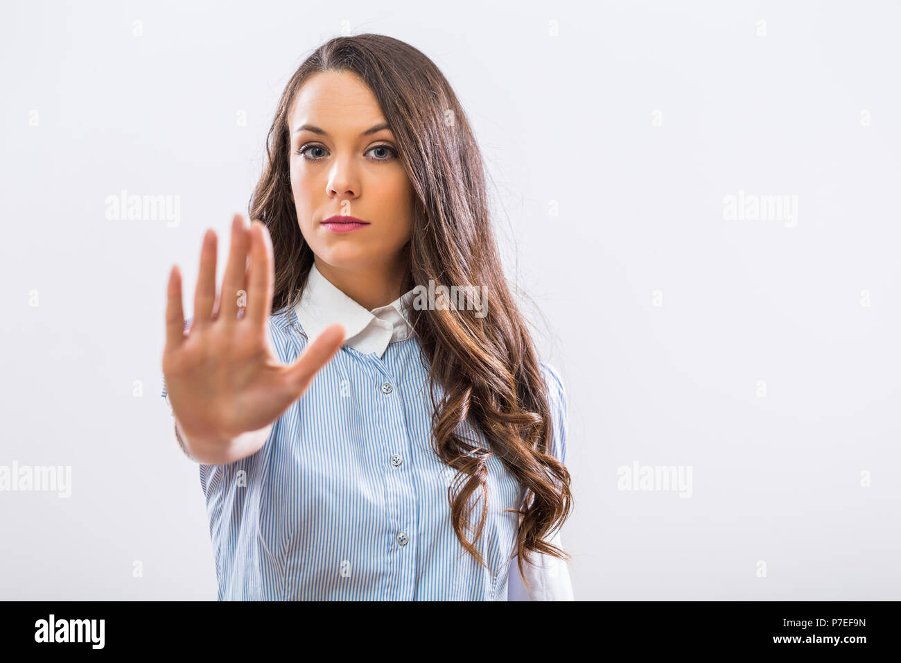 Immagine di grave imprenditrice che mostra un segno di stop su sfondo grigio. Foto Stock