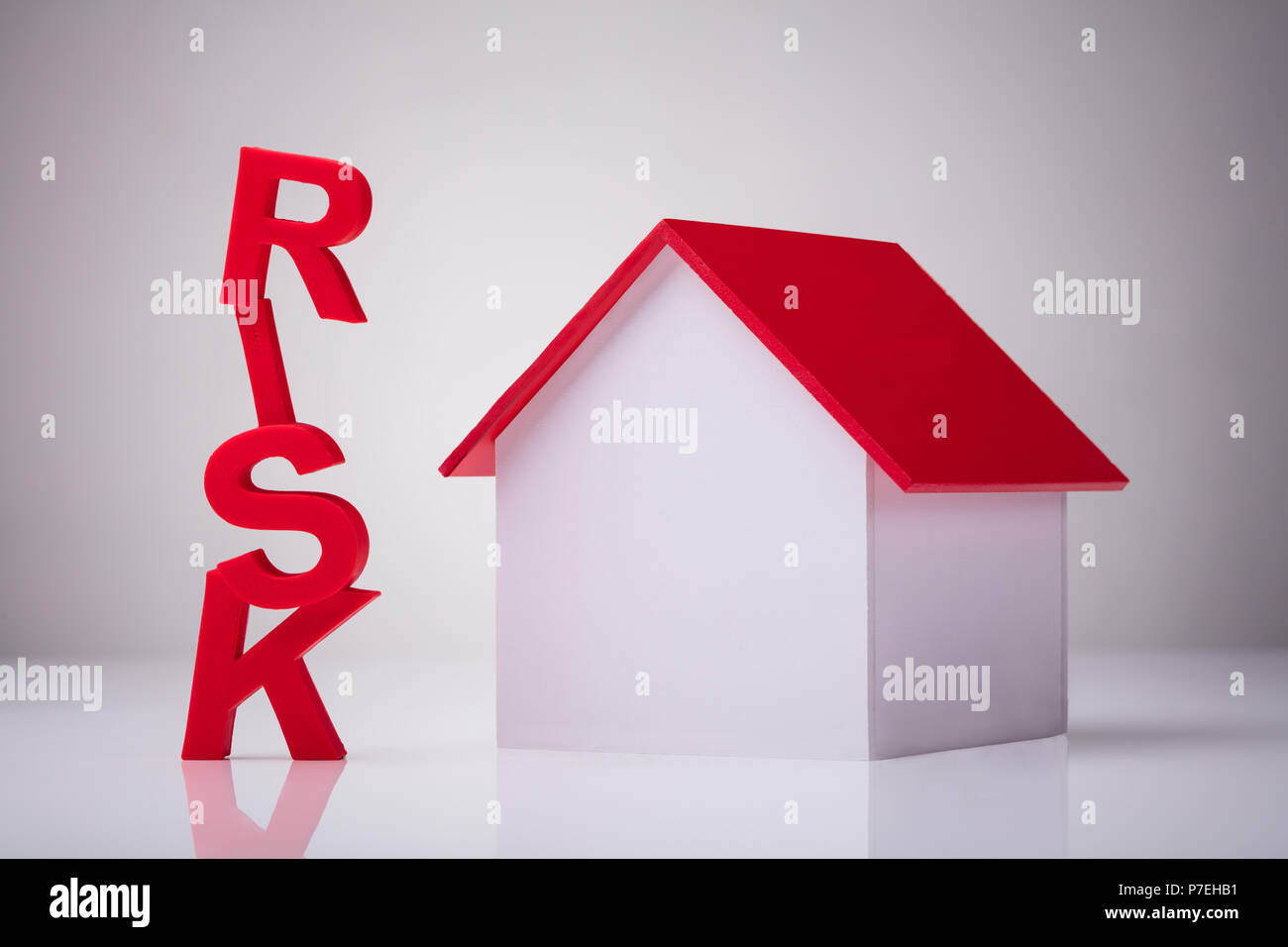 Close-up di un Rosso parola rischio vicino casa modello su sfondo riflettente Foto Stock