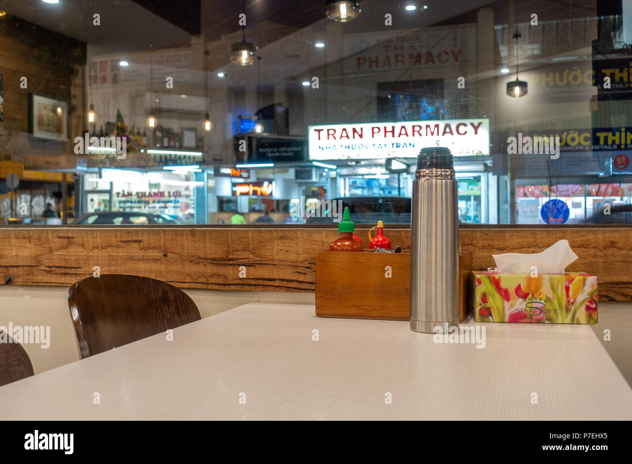 Le impostazioni di una tavola in un ristorante Vietnamita con salse, casella di tessuto e bottiglie di acqua calda. Footscray VIC, Australia. Foto Stock