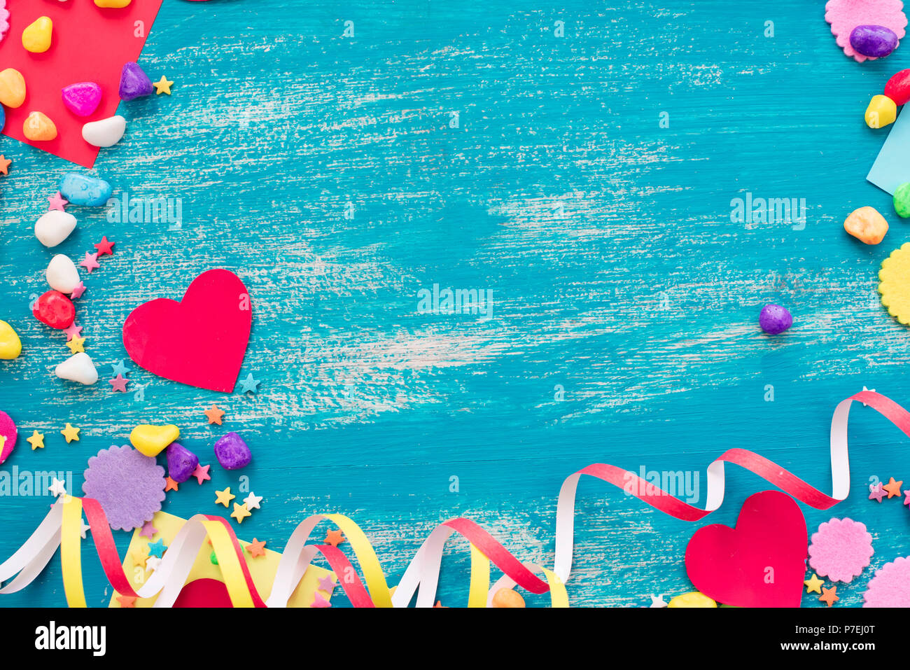 Festive coriandoli cuore di sfondo candy sature di colore. Il legno vecchio sfondo blu con spazio copia laici piatta Foto Stock