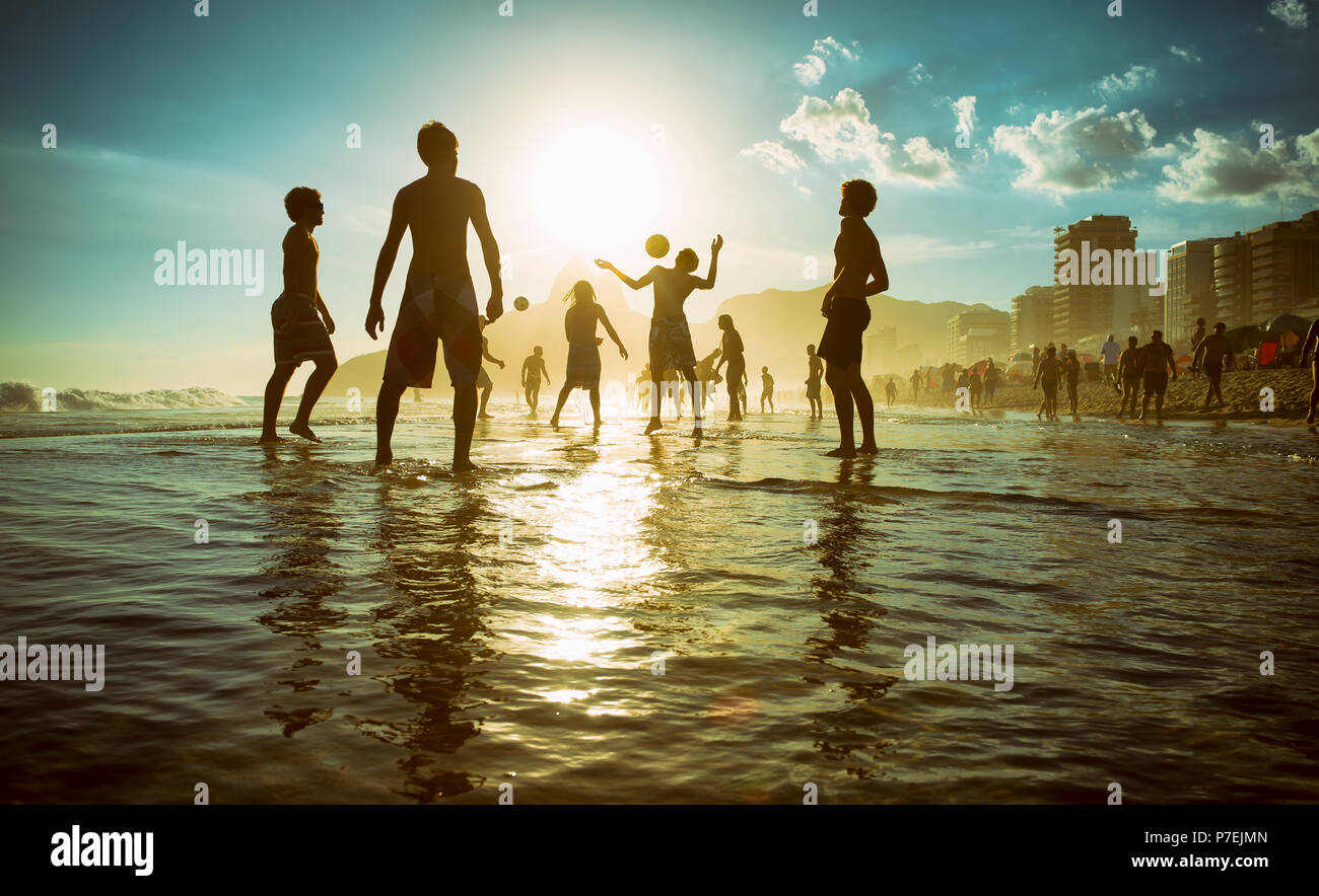 RIO DE JANEIRO - Febbraio 23, 2014: sagome di brasiliani giocando keepy uppy altinho beach soccer sul tramonto shore a posto 9 Ipanema Beach Foto Stock