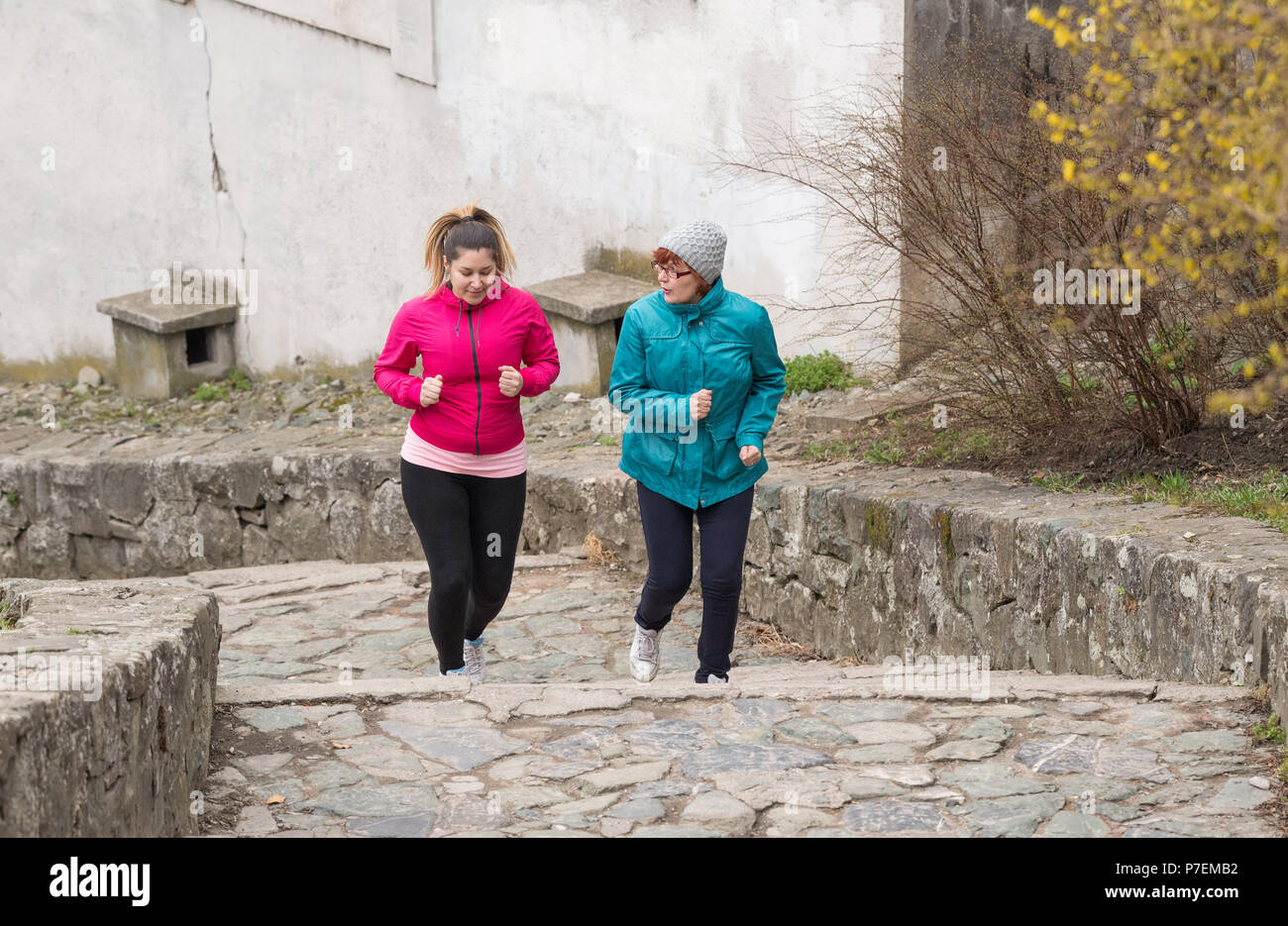 Madre e figlia indossando sportswears ed esecuzione di sopra a fortezza della città Foto Stock
