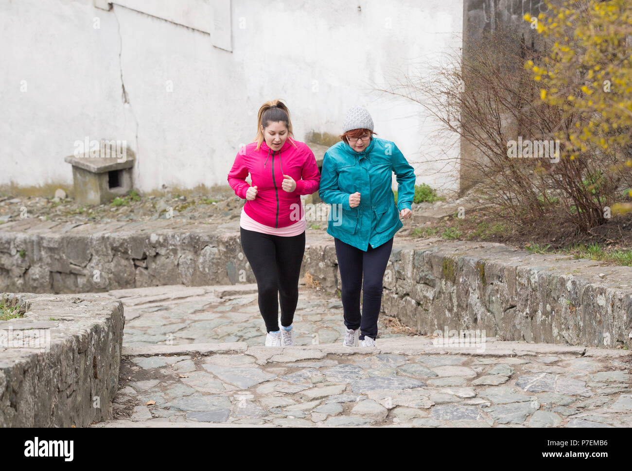 Madre e figlia indossando sportswears ed esecuzione di sopra a fortezza della città Foto Stock