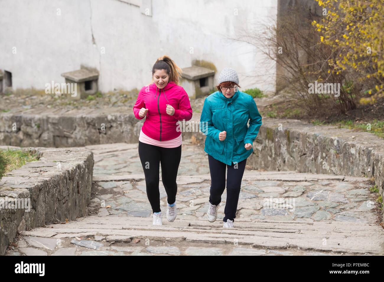 Madre e figlia indossando sportswears ed esecuzione di sopra a fortezza della città Foto Stock
