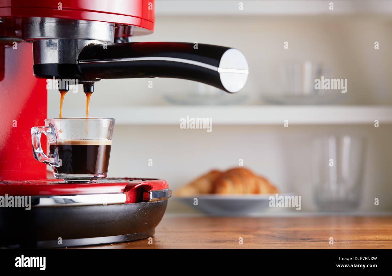 Rendendo il caffè fresco andando fuori da un caffè macchina espresso. Facendo espresso in vetro trasparente tazza di caffè. Foto Stock