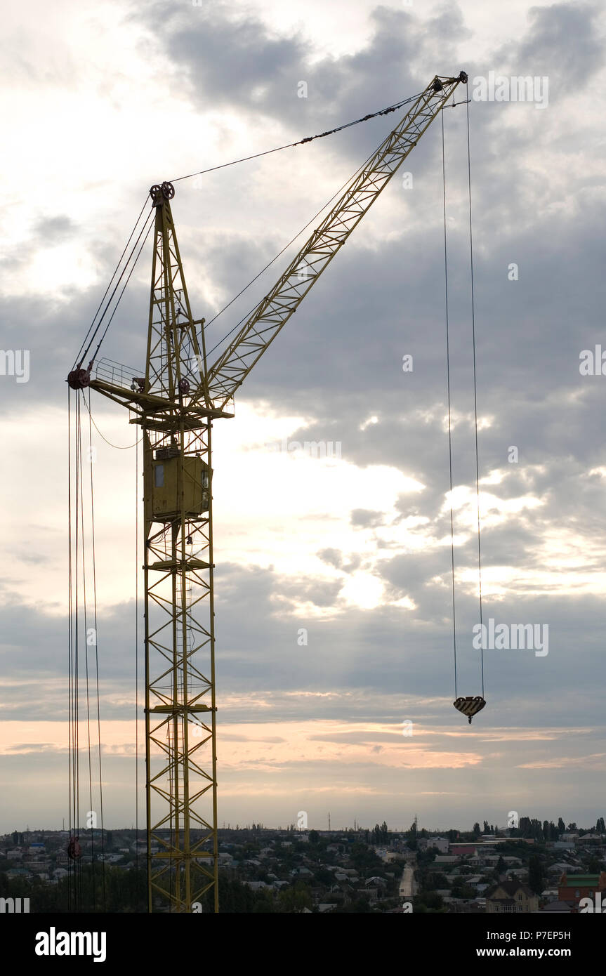 Industrial gru per edilizia e costruzione di sagome su sun a sunrise. Foto Stock