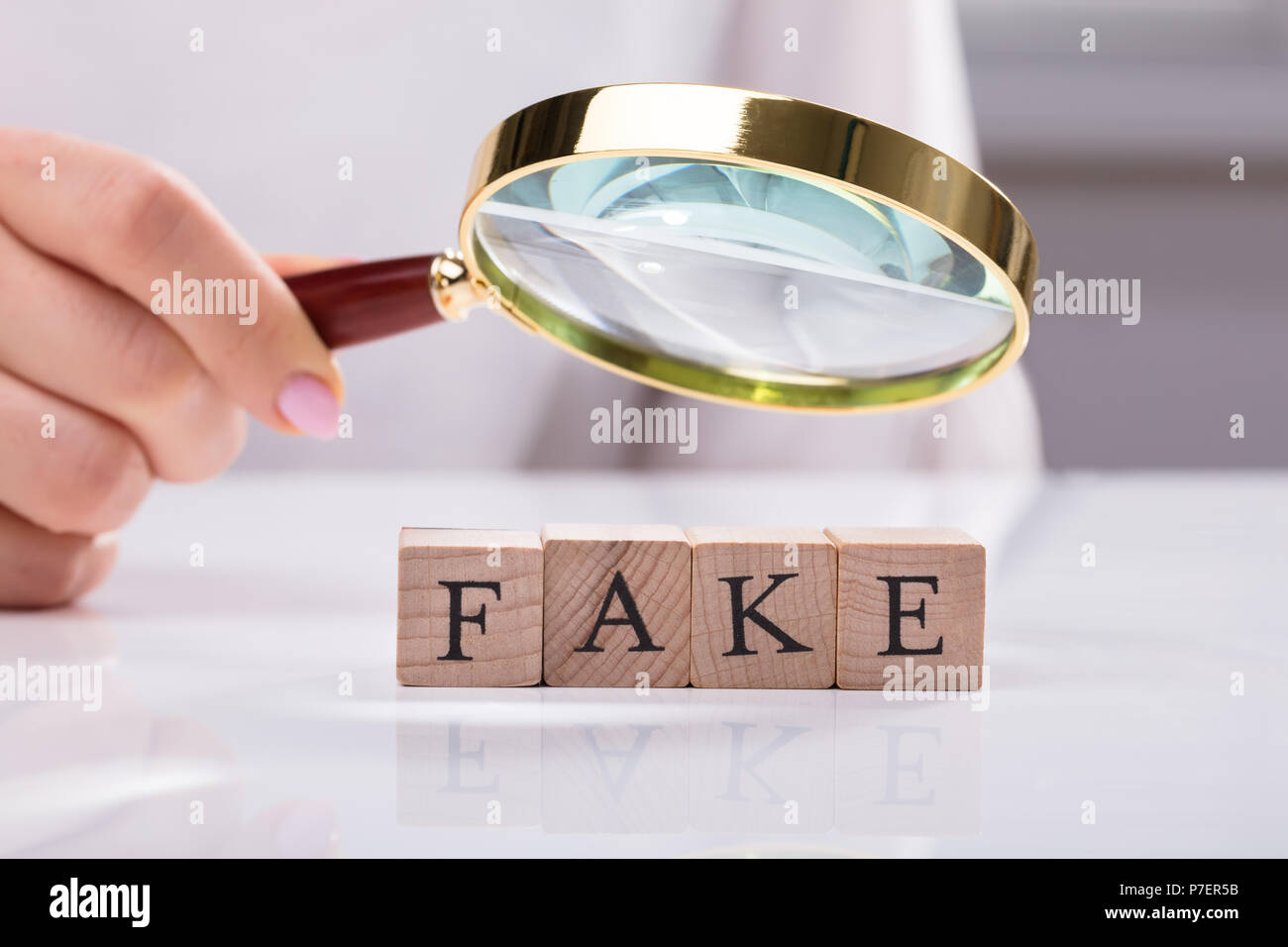 Close-up di una imprenditrice la mano di esaminare i blocchi di legno che mostra Fake parola Foto Stock