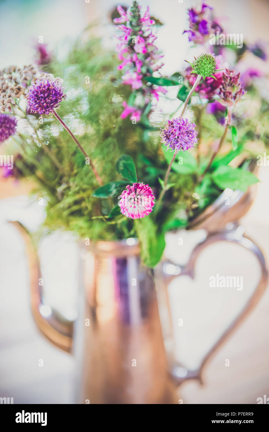 Home reso selvatici freschi bouquet di fiori in vaso in argento su tavola di legno Foto Stock