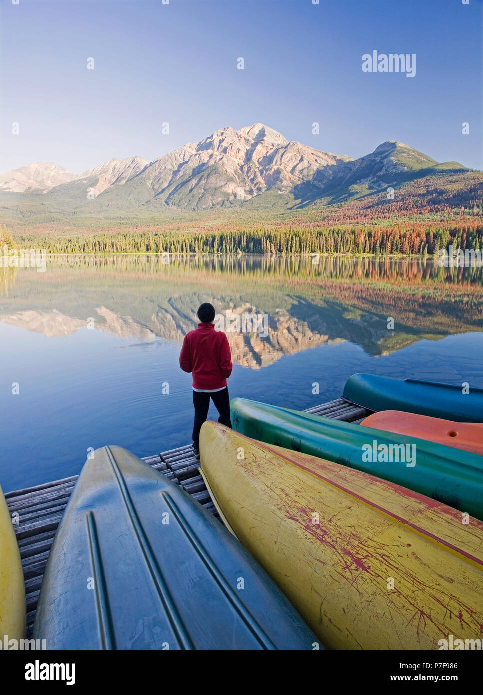 Lone medio di sesso maschile di età in piedi sul dock con canoe guardando a piramide in Montagna Lago Piramide, il Parco Nazionale di Jasper, Alberta, Canada. Foto Stock