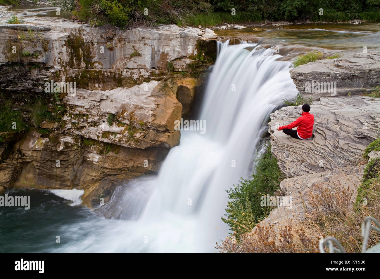 Metà maschio età meditando accanto alla cascata, Lundbreck cade, Alberta, Canada. Foto Stock