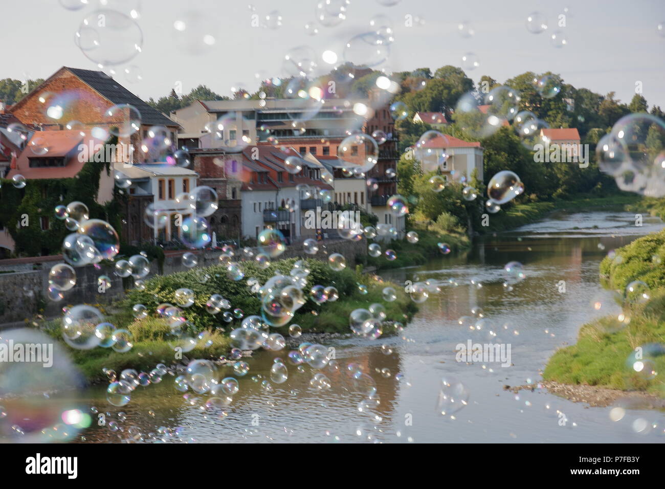 Magica, unreal, paesaggio da sogno con bolle di sapone tenda in aria oltre il fiume e la città con le case, edifici Foto Stock