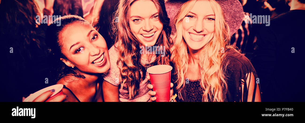 Amici di sesso femminile con tazze monouso in club Foto Stock