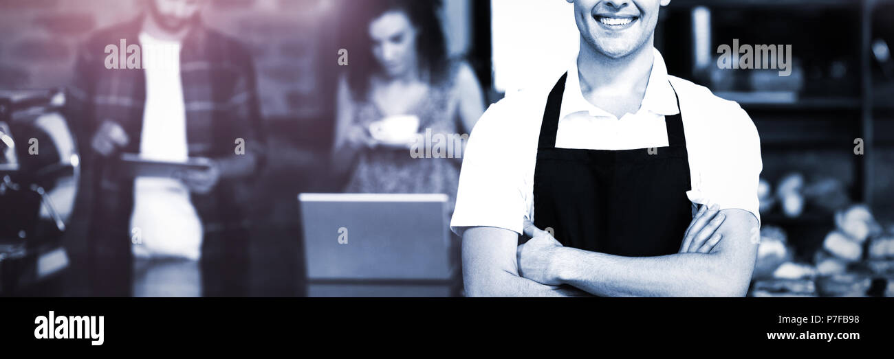 Barista sorridente con le braccia incrociate di fronte ai clienti Foto Stock