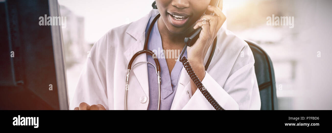 Medico donna al telefono mentre si utilizza il computer Foto Stock