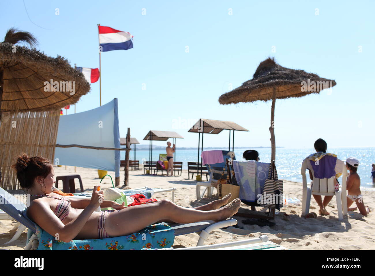 Ragazza europea copre il corpo con protezione solare lozione sulla spiaggia nel popolare e conveniente resort di Hammamet in Tunisia di Riva del Mediterraneo Foto Stock