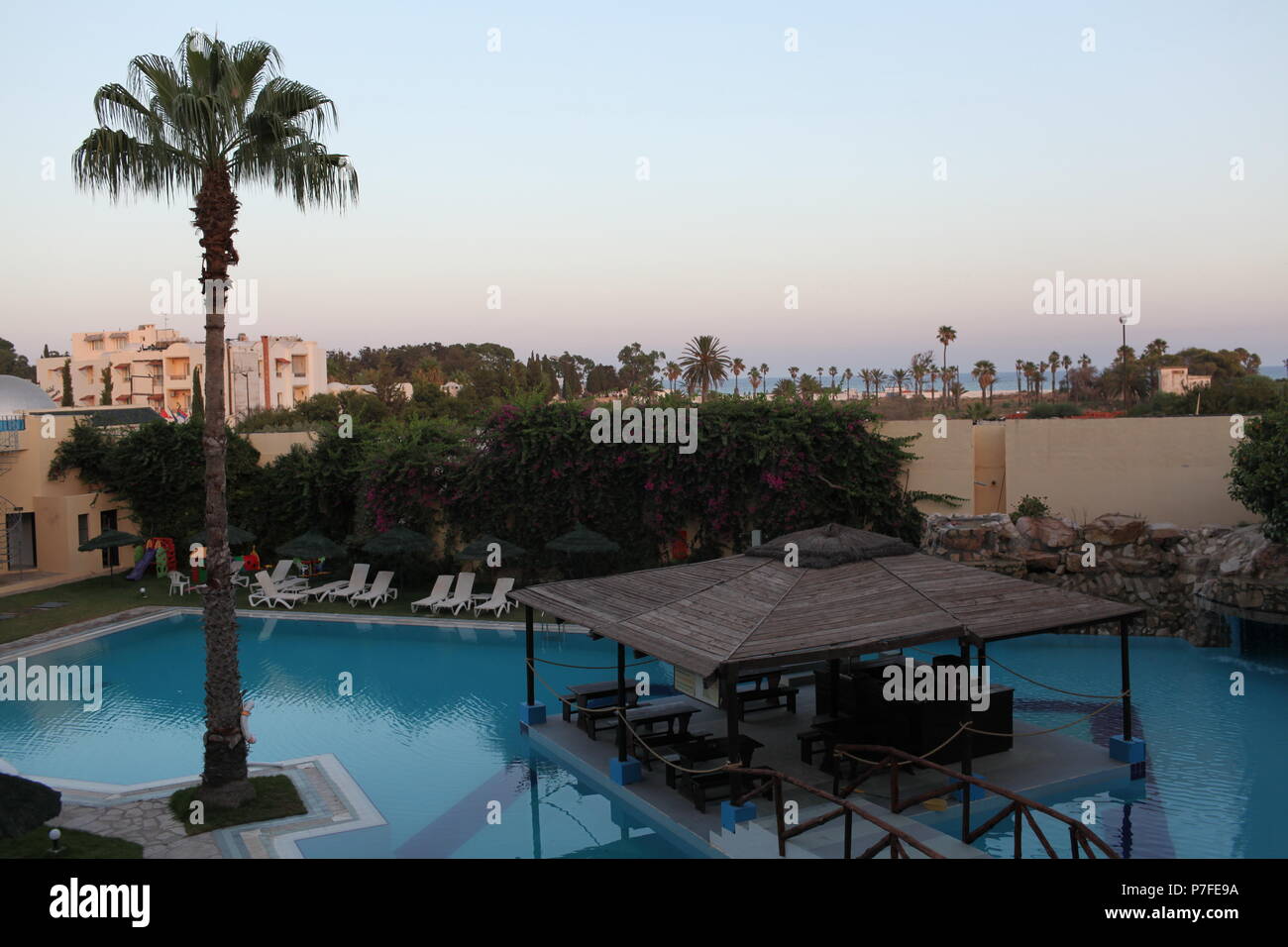 Un estate vista tramonto da una hotel Mediterraneo balcone sulla riva del mare ad Hammamet, Tunisia, palme e una piscina sul territorio dell'hotel Foto Stock