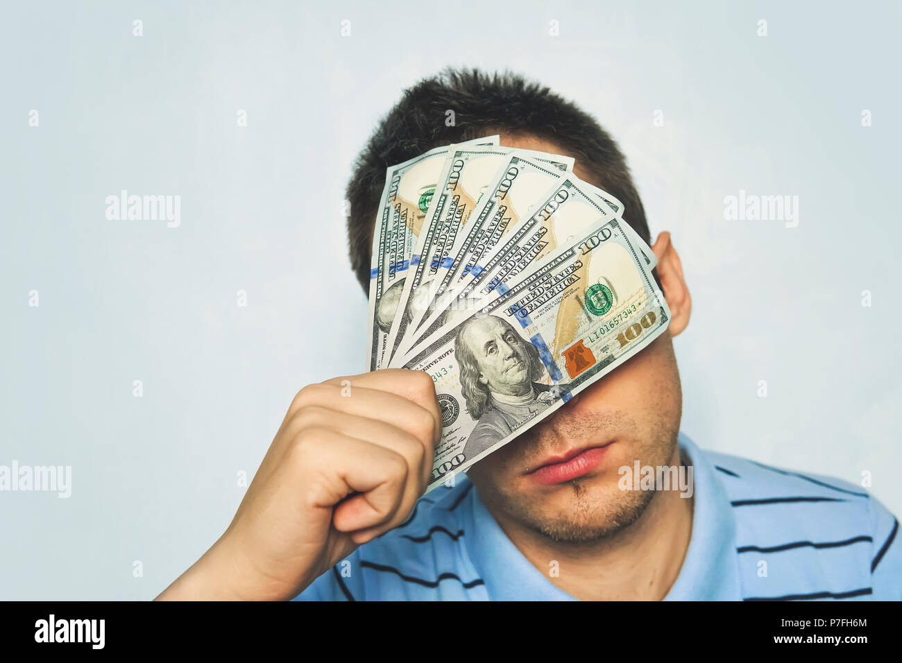 Un uomo nasconde i suoi occhi per il denaro. Imprenditore con dollar banconota nastrato per gli occhi, la fotografia in studio nel concetto di corruzione. Foto Stock