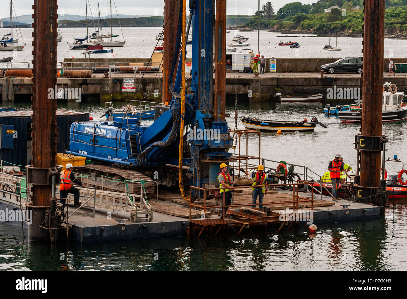 Schull, West Cork, Irlanda. 6 Luglio, 2018. Lavoratori edili e ingegneri di controllare la posizione della costruzione chiatta per facilitare l'installazione di pali che supporterà il nuovo pontile in Schull Harbour. Il lavoro è prevista per le 4 settimane e costano circa € 500.000. Credito: Andy Gibson/Alamy Live News. Foto Stock