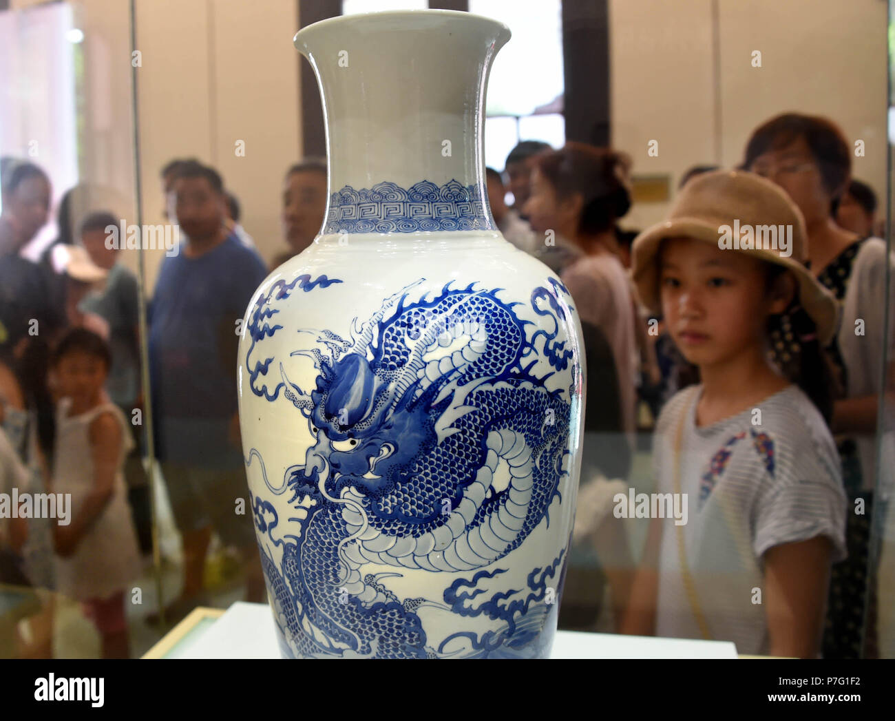 Qingdao, Cina Shandong. 6 Luglio, 2018. Ai visitatori di visualizzare un blu-bianca porcellana di forno imperiale durante una mostra di reliquie culturali dal Museo Palazzo svoltasi a Qingdao Art Museum a Qingdao, Cina orientale della provincia di Shandong, Luglio 6, 2018. La mostra è stata aperta gratuitamente al pubblico Venerdì e durerà per luglio 28. Credito: Li Ziheng/Xinhua/Alamy Live News Foto Stock