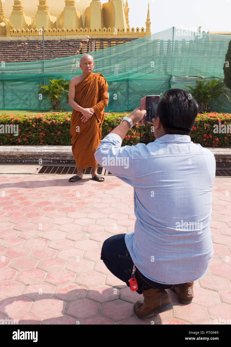 Uomo di scattare una foto del monaco buddista di Wat Pha That Luang tempio, Vientiane, Laos, Asia. Foto Stock
