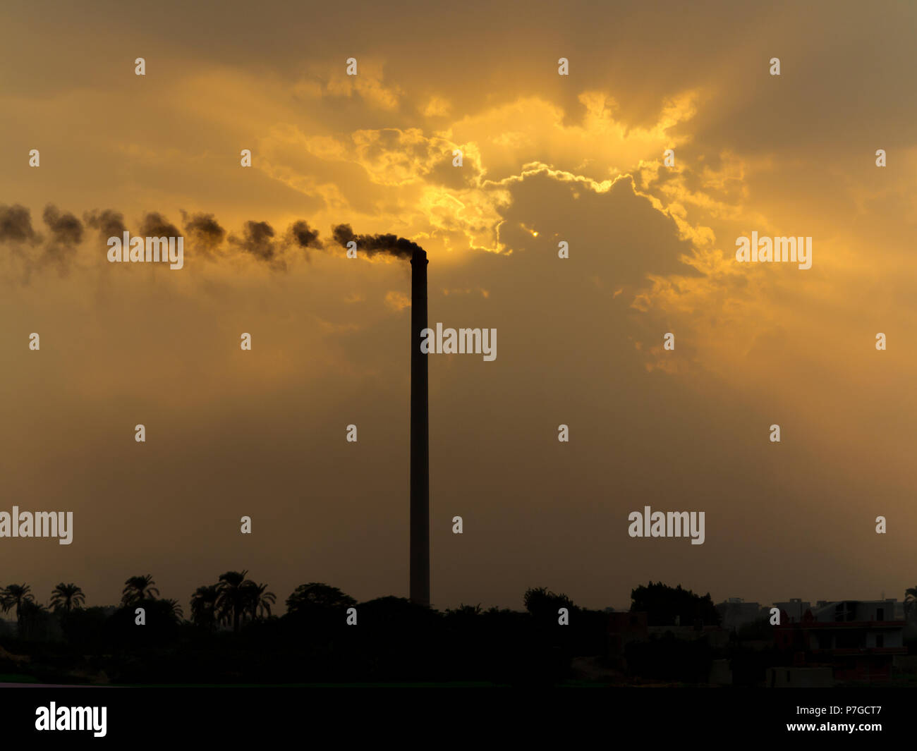 Tramonto sul fiume Nilo in Egitto in una zona industriale con inquinamento causato dal fumo di camino aumentando il drammatico colori arancione tra le nuvole Foto Stock