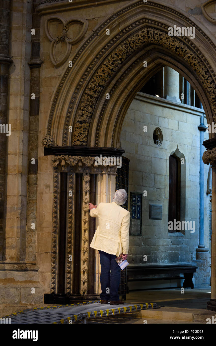 Un uomo guarda attentamente in corrispondenza di un arco decorato sul sud del corridoio della cattedrale medievale, Lincoln, Inghilterra. Foto Stock