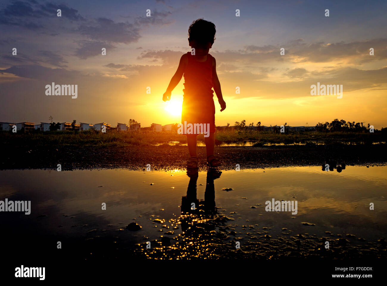 Silhouette asiatica di capretto e la riflessione del tramonto, un ragazzo silhouette Foto Stock