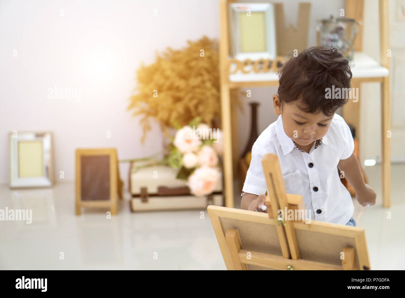 Un grazioso piccolo ragazzo asiatico scrivere su una lavagna. Foto Stock