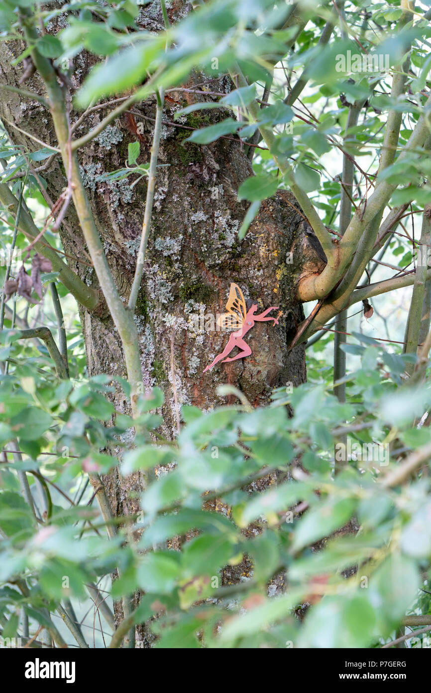 Guardando attraverso il fogliame in una fata rosa su una struttura ad albero Foto Stock