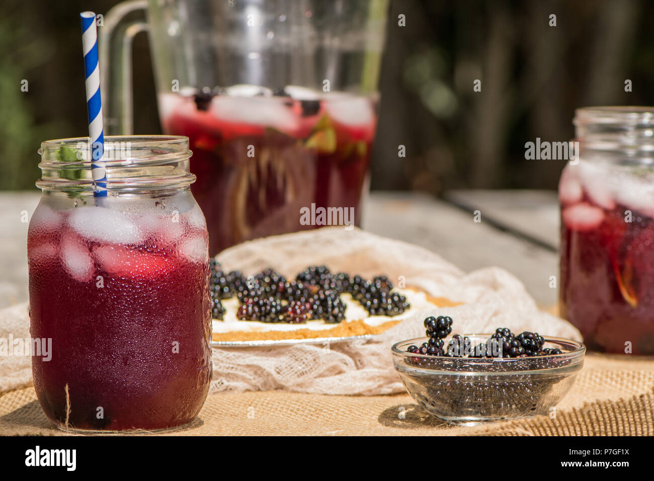 Canning jar bicchieri e brocca di blackberry tè freddo con una cheesecake Foto Stock