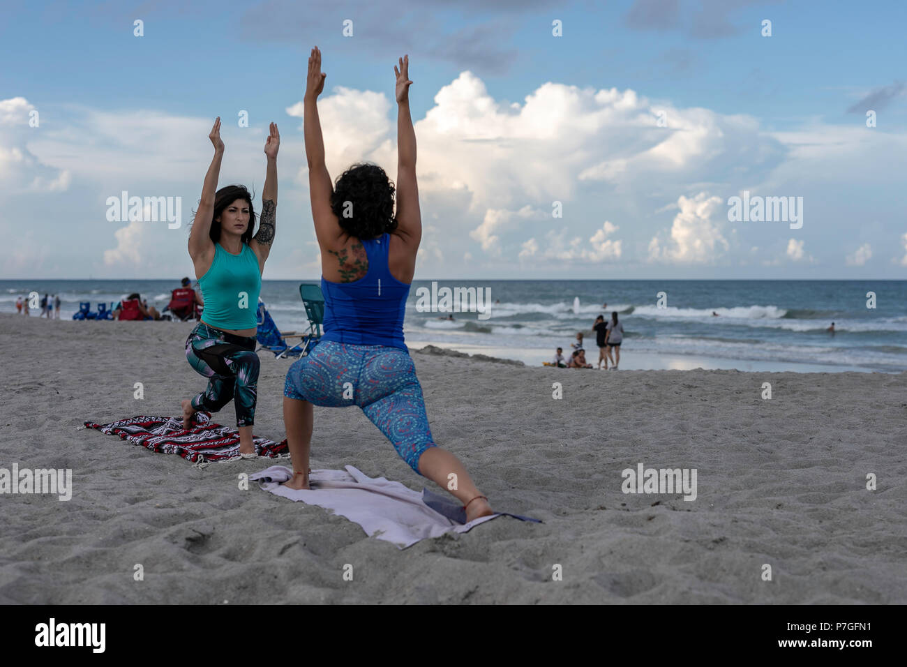 Due giovani donne facendo un allenamento di yoga sulla spiaggia indossando pantaloni di yoga e Canotte Foto Stock