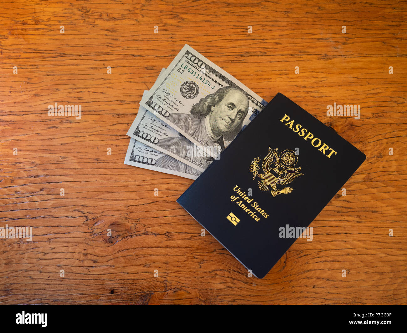 Un blu navy US passport con trecento le fatture del dollaro. Fotografato su una tavola di legno. Foto Stock