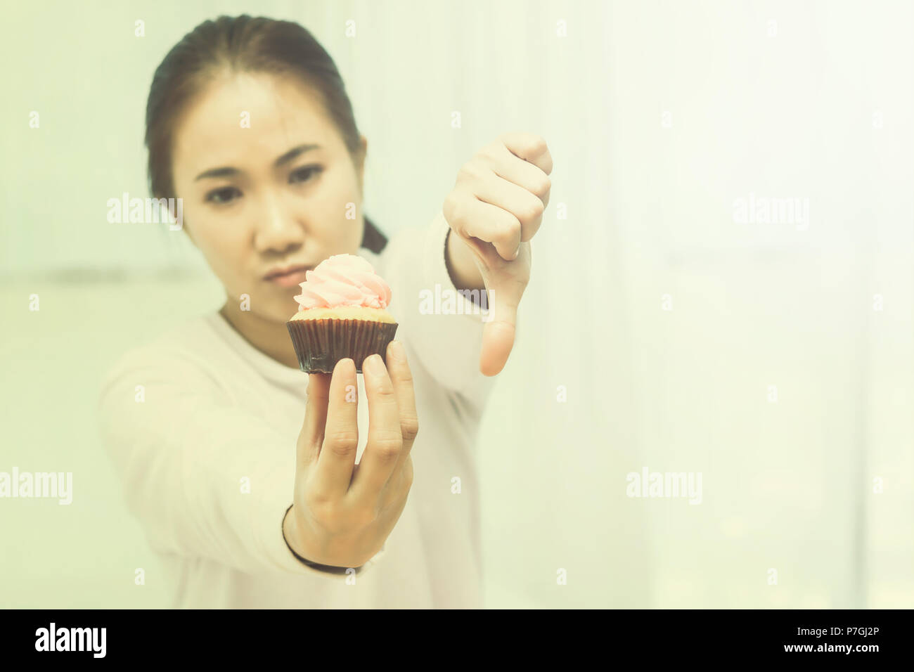 Donna asiatica sulla dieta per una buona salute concetto.dire no Cup cake e il cibo spazzatura.Tono colore Foto Stock