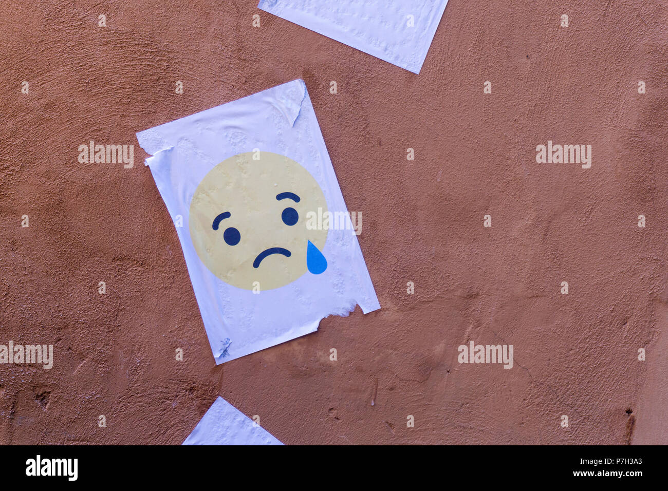 Il pianto carattere emoji stampato su carta e bloccati su una parete Foto Stock