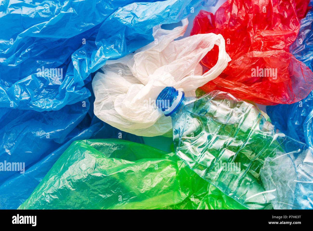 Pila di variopinti sacchetti di plastica e una bottiglia, il consumismo e l'inquinamento ambientale concetto Foto Stock