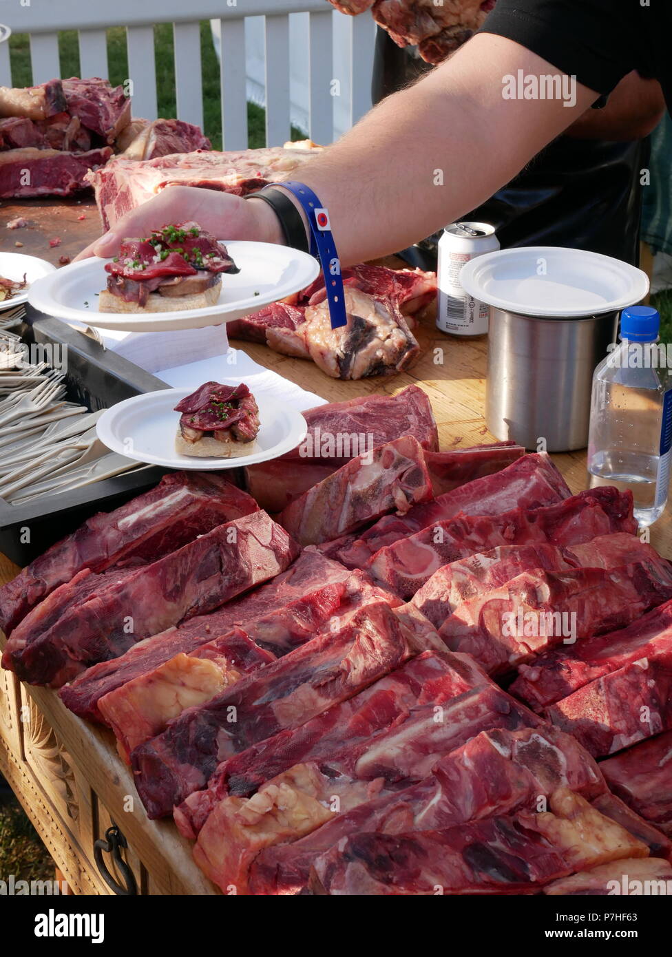 Un uomo serve piccole piastre di cibo fatto dai primi tagli di carni bovine al gusto di Londra food festival, Regents Park, Londra, Inghilterra. Foto Stock
